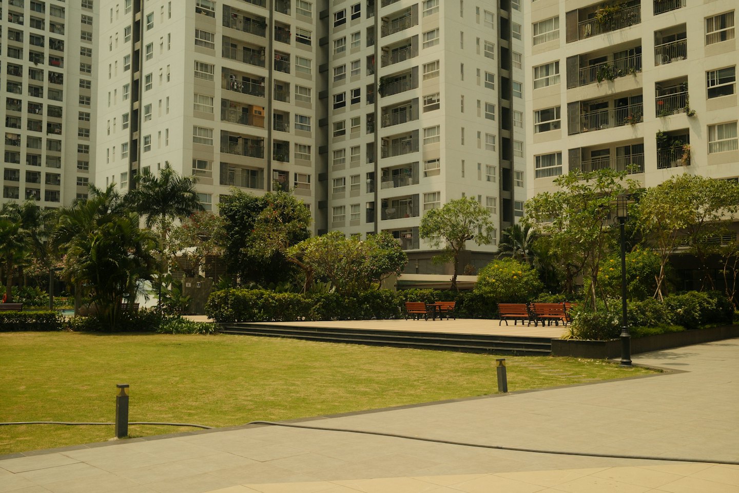 Modern apartment complex with a green lawn and park benches.